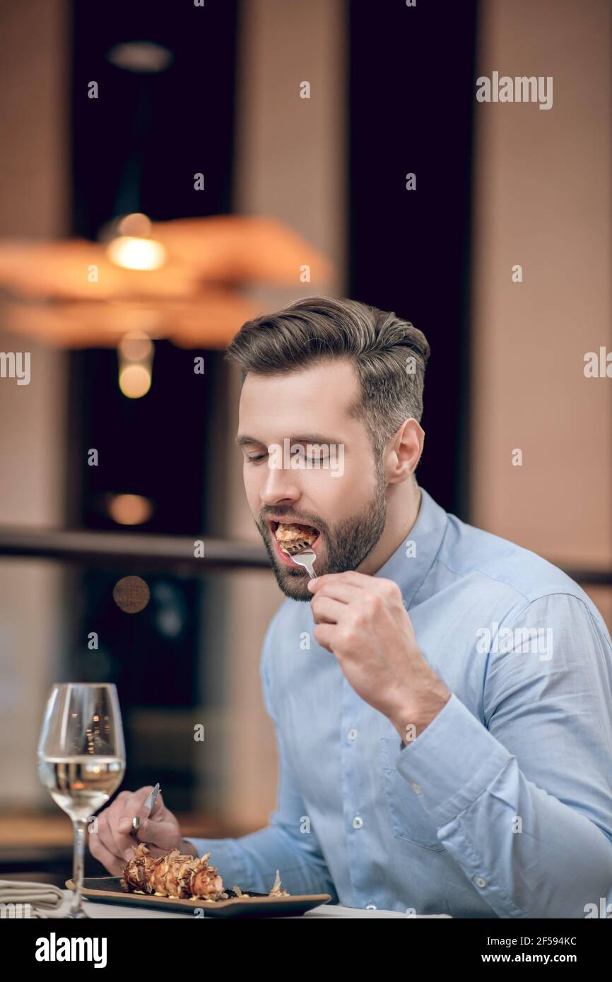 Bearded man eating seafood at the restaurant and looking involved Stock Photo