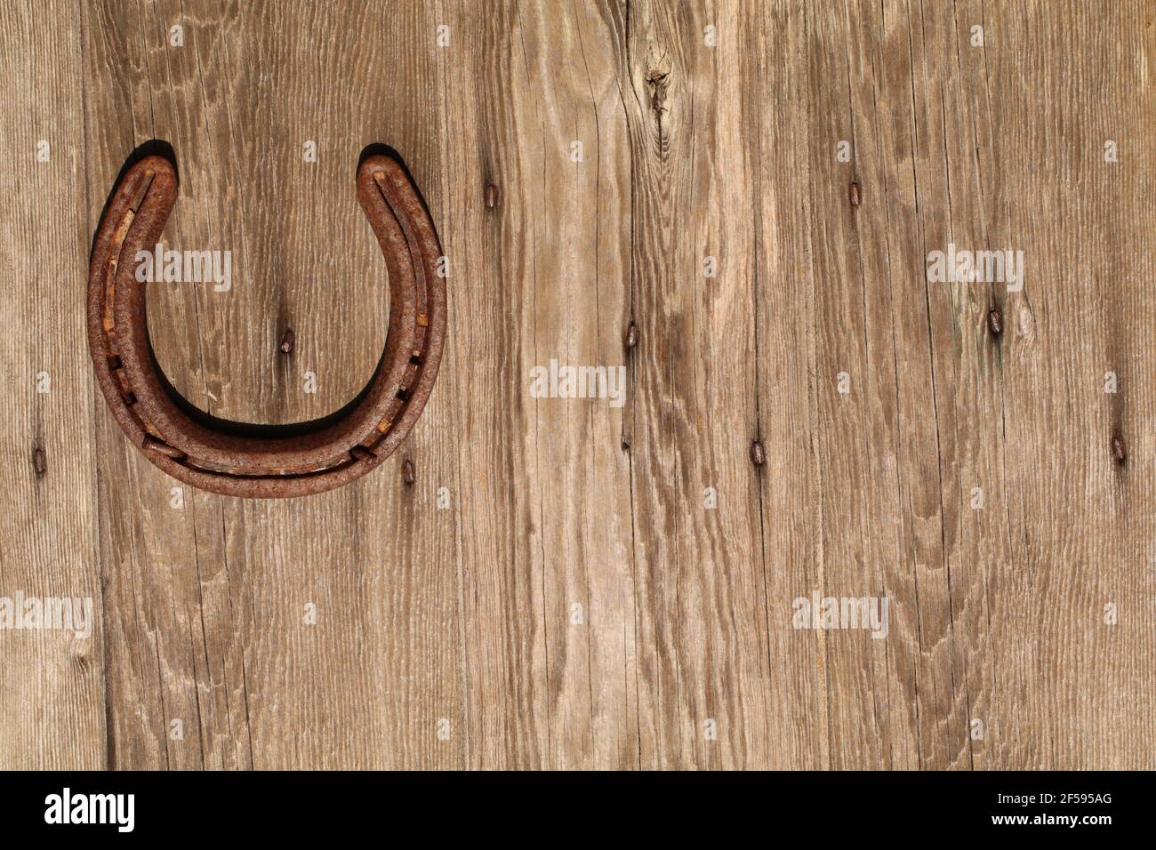 Horseshoe middle left of frame on a wood grain patterned door symbol of good luck Stock Photo