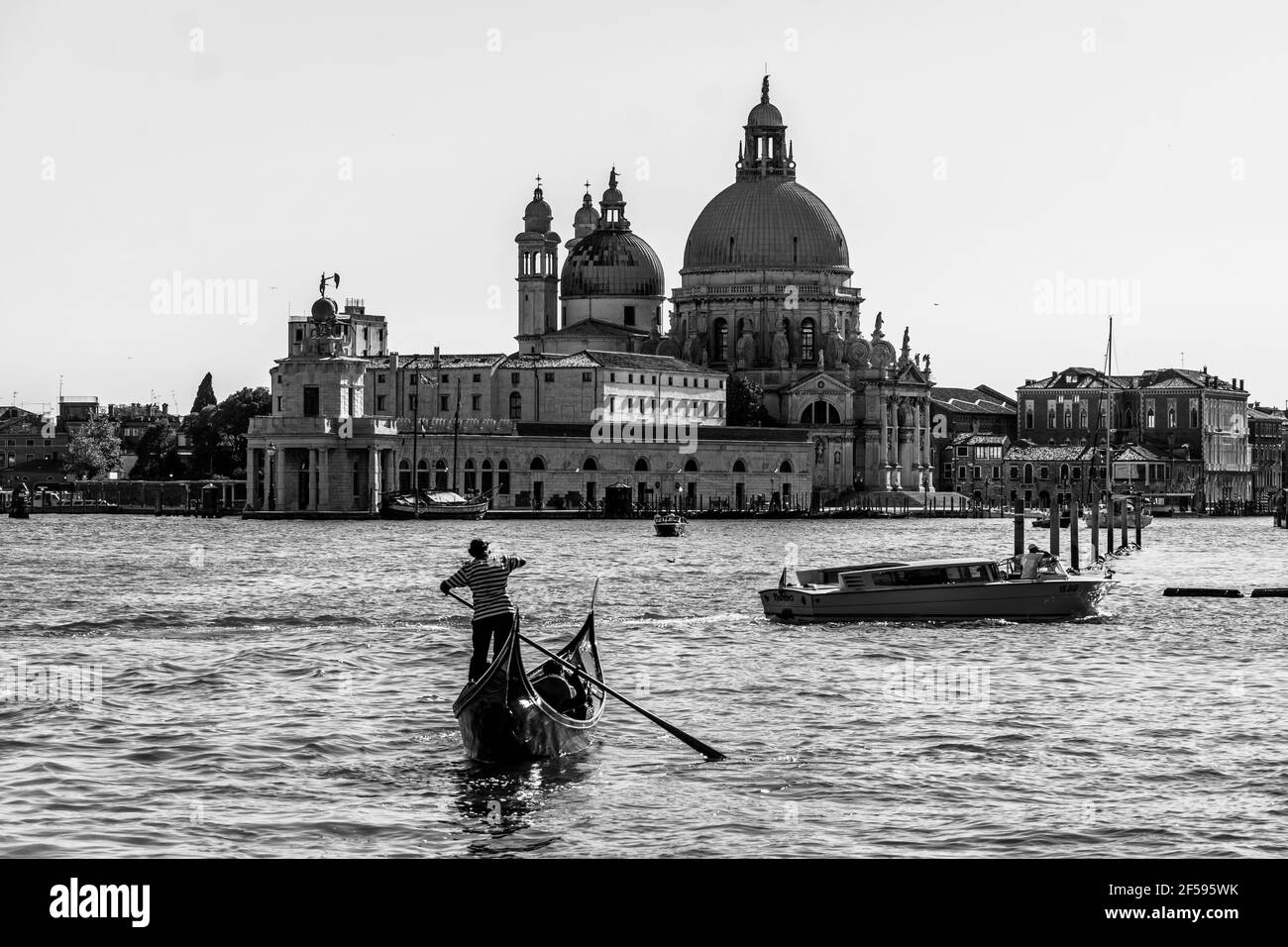 Venice, Italy - June 22 2020: A classic black and white view of a traditional gondola that sails on the Venice Grand Canal with the Basilica di Santa Stock Photo