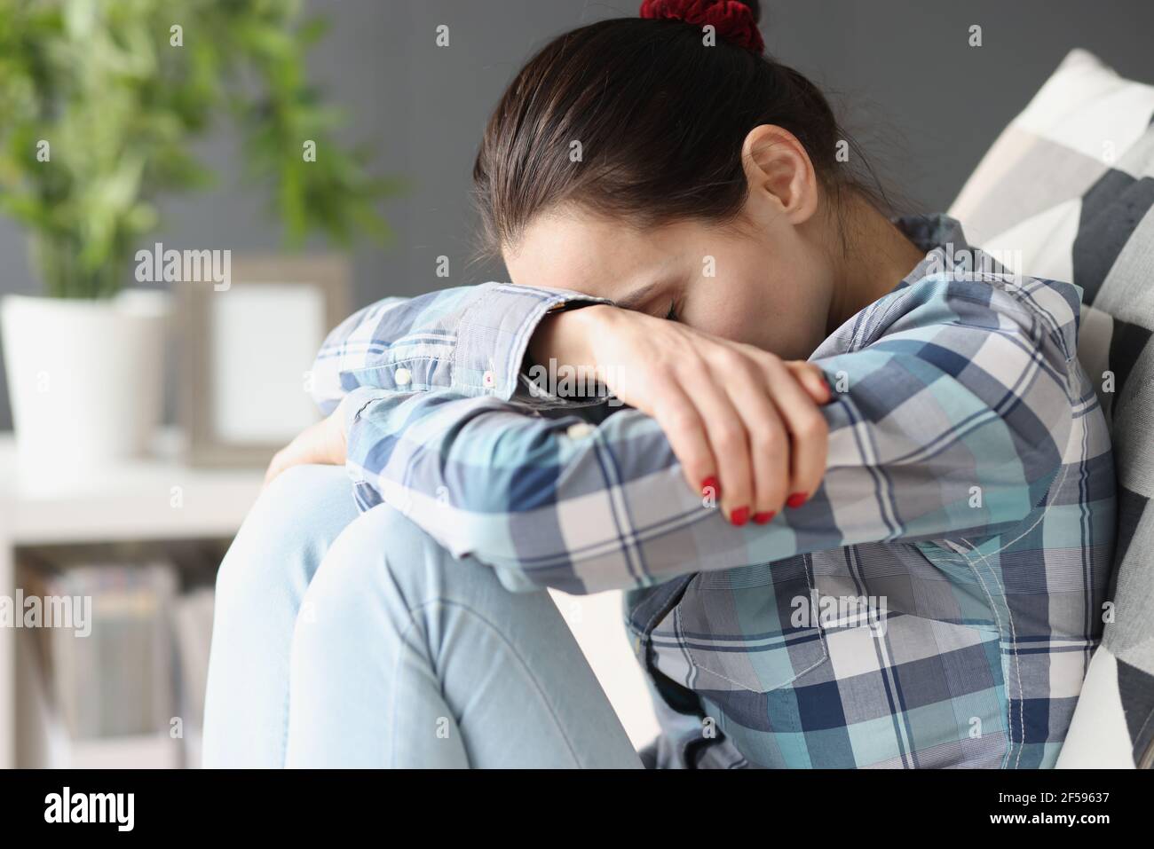 Sad woman sitting with her head bowed on sofa Stock Photo Alamy