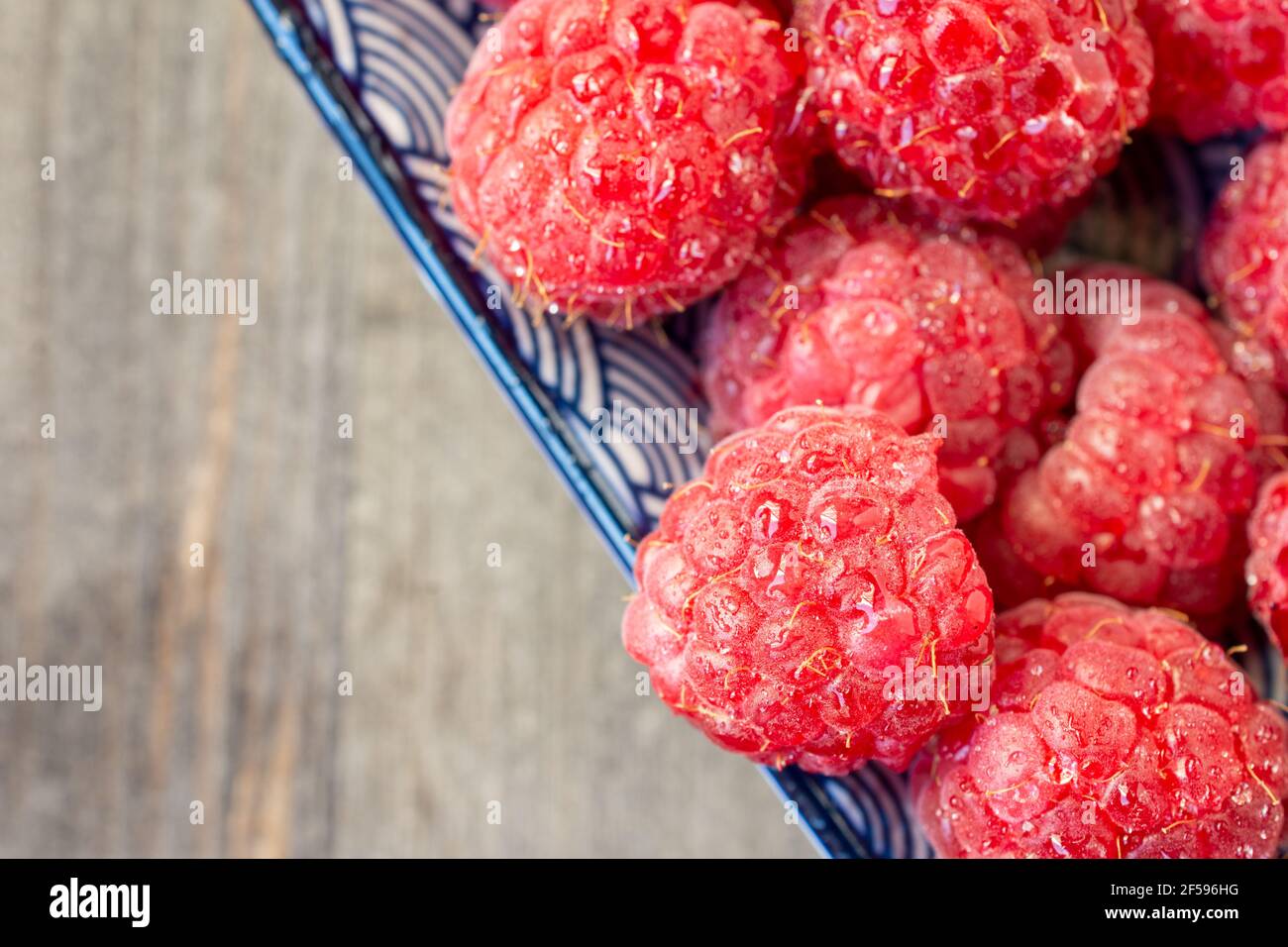Horizontal Rasberries Diagonal aerial view of wet raspberries on blue plate, selective focus ...