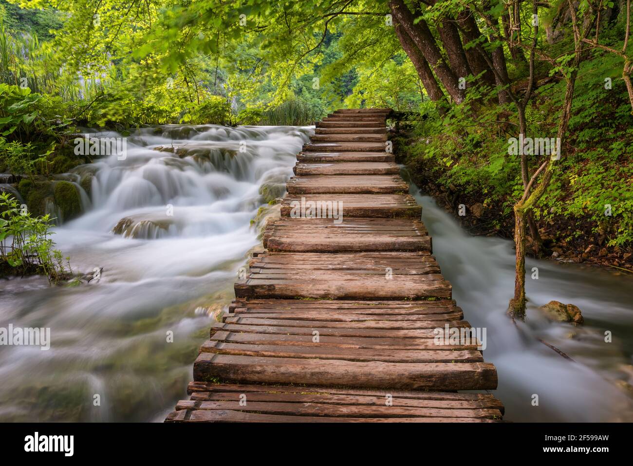 Beautiful view of waterfalls with turquoise water and wooden pathway through over water. Plitvice Lakes National Park, Croatia. Famous attraction Stock Photo
