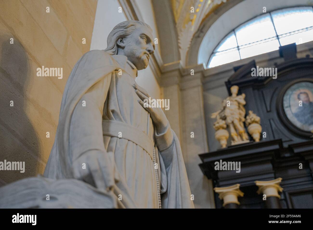 The sculpture of a religious man with his hand placed on his heart in the Catholic church interior under natural light, Krakow, Poland Stock Photo