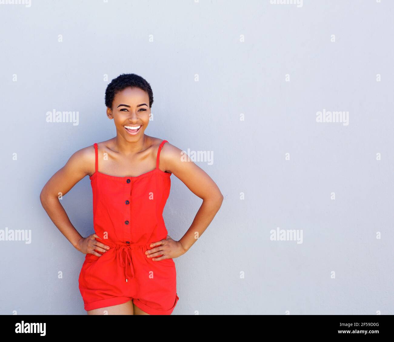 Portrait of cooly young african american woman laughing against gray wall Stock Photo