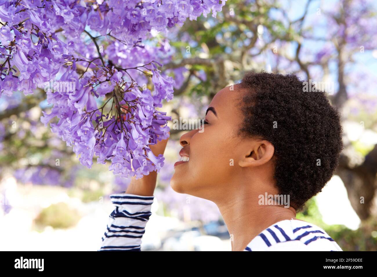 Portrait of young black woman smelling flowers on tree Stock Photo - Alamy