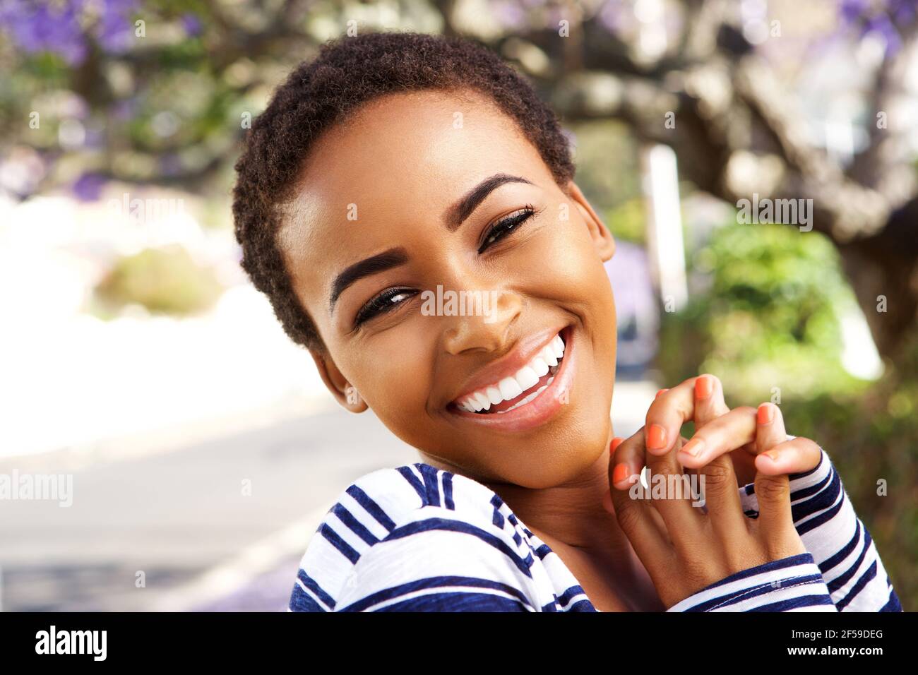 Close up portrait of beautiful young black woman smiling outside in ...