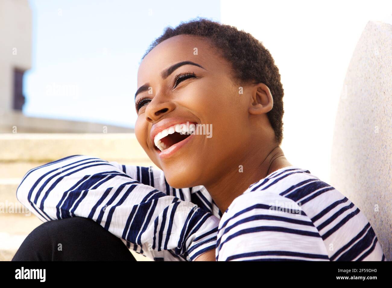 Close up portrait of attractive young black woman laughing outside ...