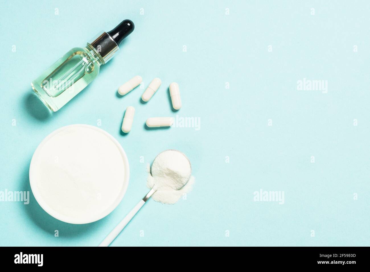 Collagen powder, capsules and serum at blue. Stock Photo