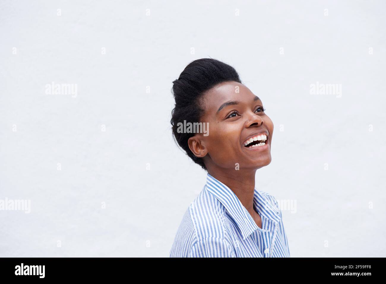 Close up portrait of young black woman laughing against white ...