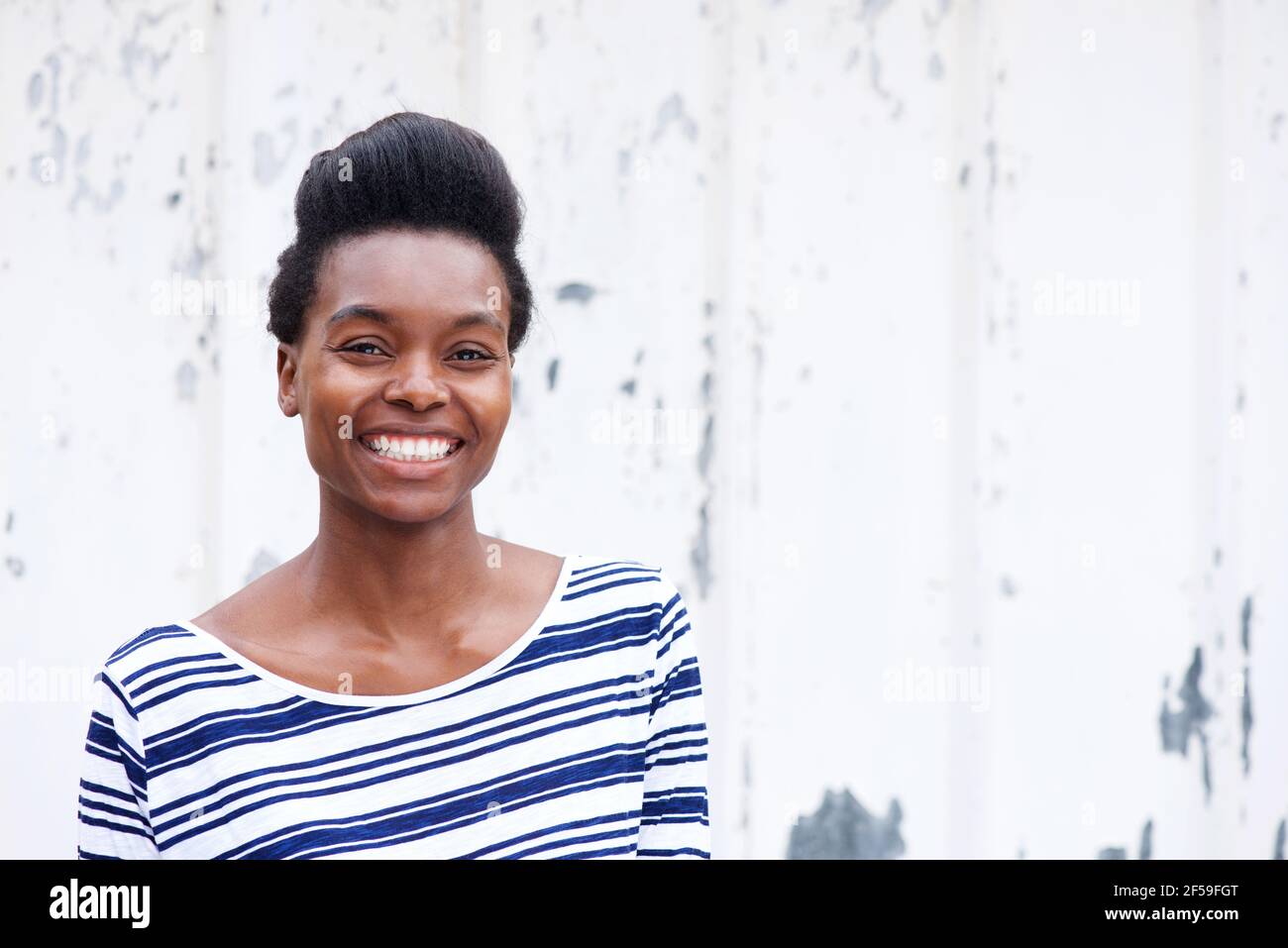 Portrait of smiling young african woman against white wall Stock Photo ...
