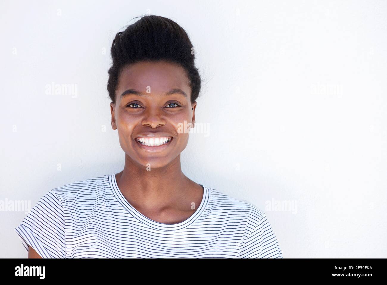 Close up portrait of beautiful young black woman smiling against white ...