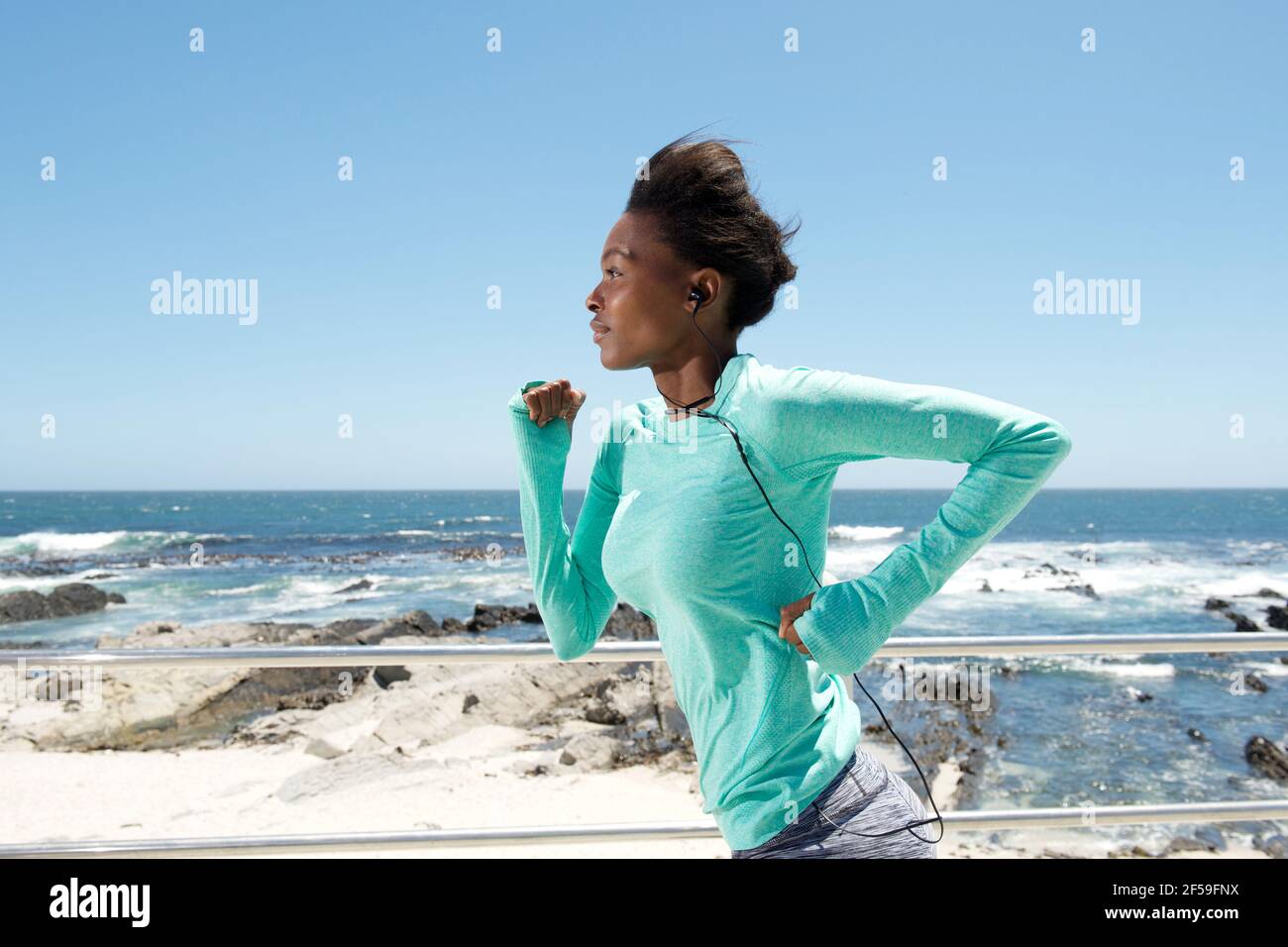 Side portrait of active young black woman running by the sea Stock ...
