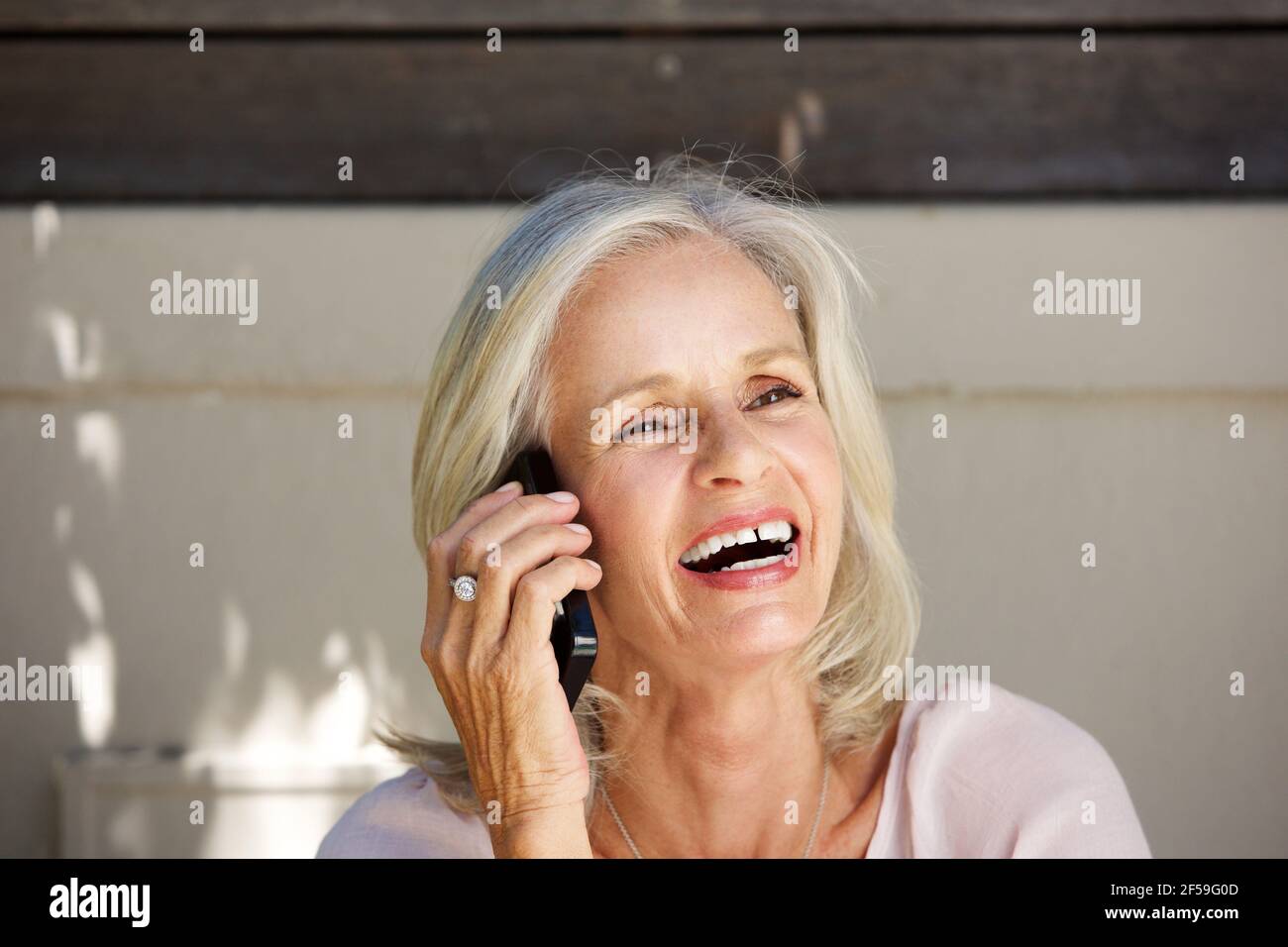 Close up portrait of beautiful older woman laughing on cell phone outside Stock Photo