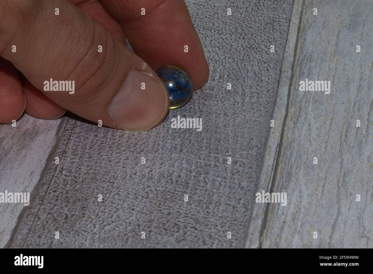 glass marble held by fingers on wooden background Stock Photo