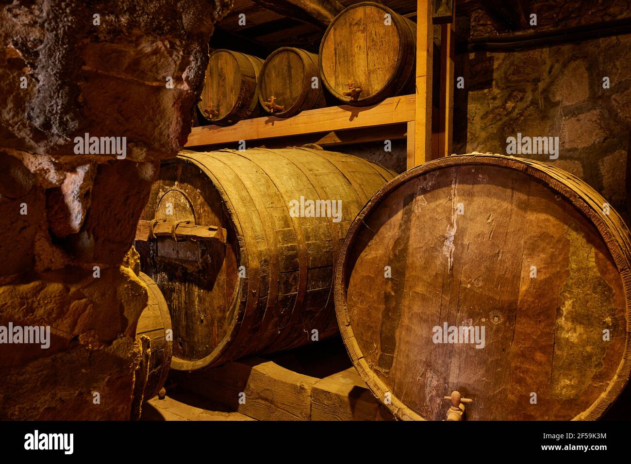 Wine barrels and casks with kegs on shelve in old wine-cellar Stock Photo