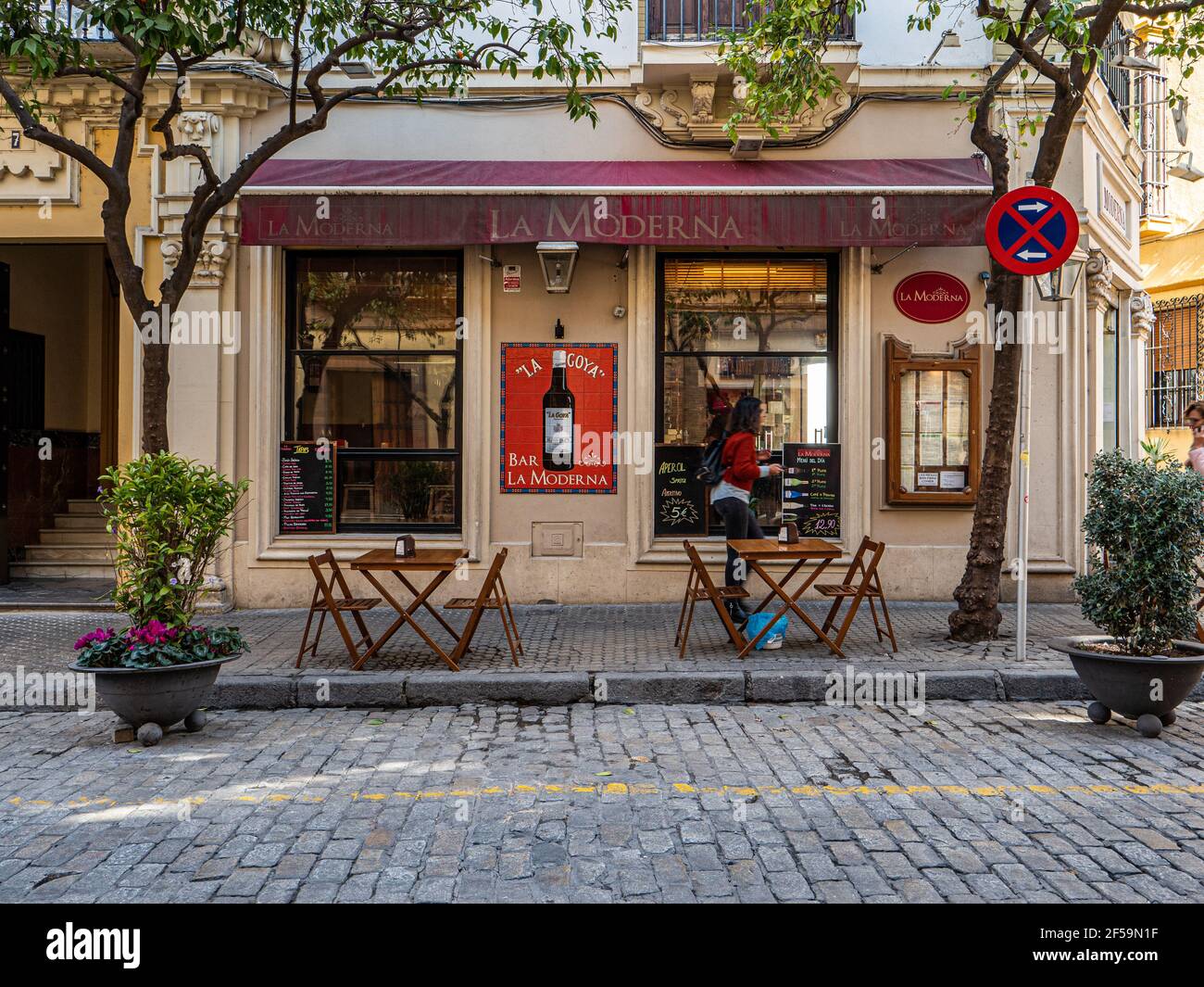 Tables and chairs set on a pavement in front of a bar Seville Spain Stock Photo