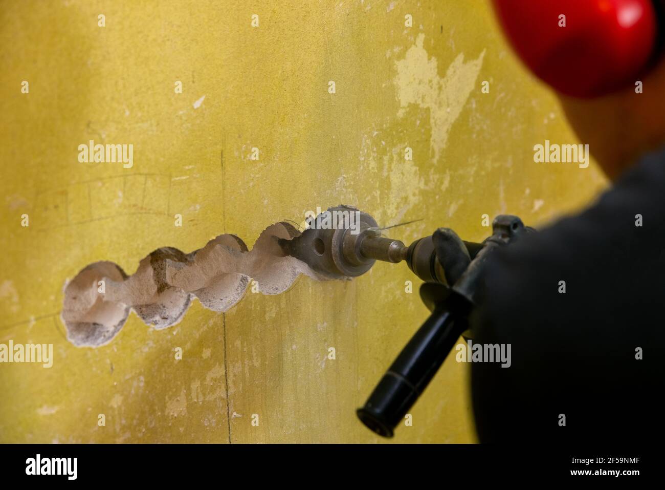worker drilling hole for electrical socket in concrete brick wall. wiring renovation Stock Photo