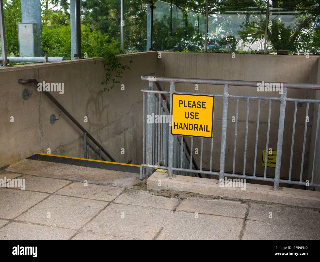 A Please Use Handrail sign on handrails in a stairwell leading to an underground car park at The Mall shopping centre at Cribbs Causeway near Bristol, England. Stock Photo