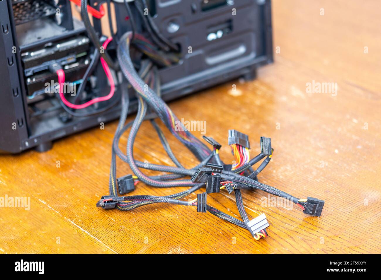 bunch of computer power supply wires sticking out from opened black pc case - close-up with selective focus. Stock Photo