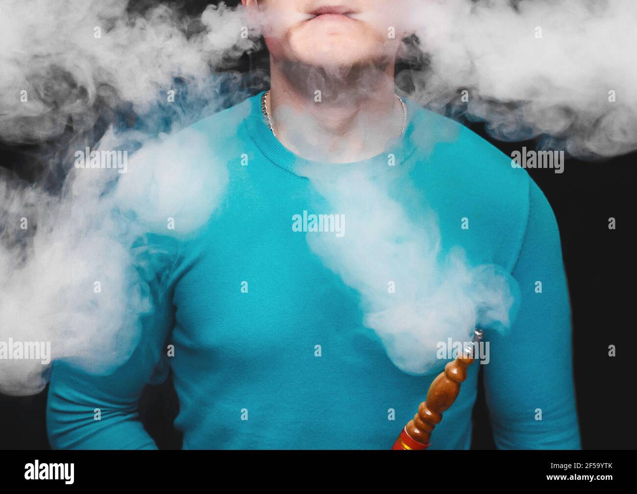 An adult guy smokes a hookah and makes a lot of white smoke, close-up. Stock Photo