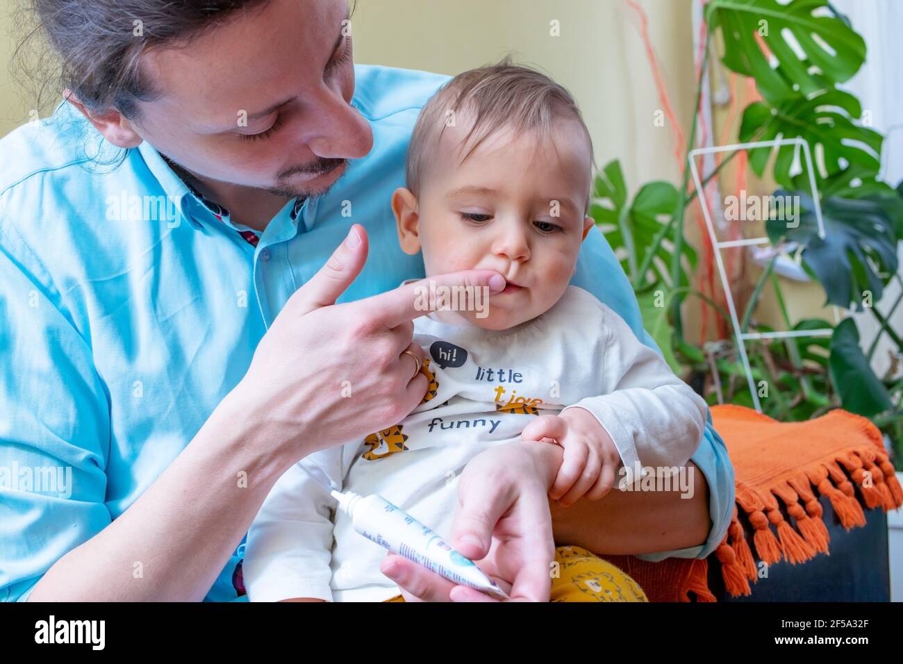 Father rubbing pain relieving gel into his little baby boy's growing