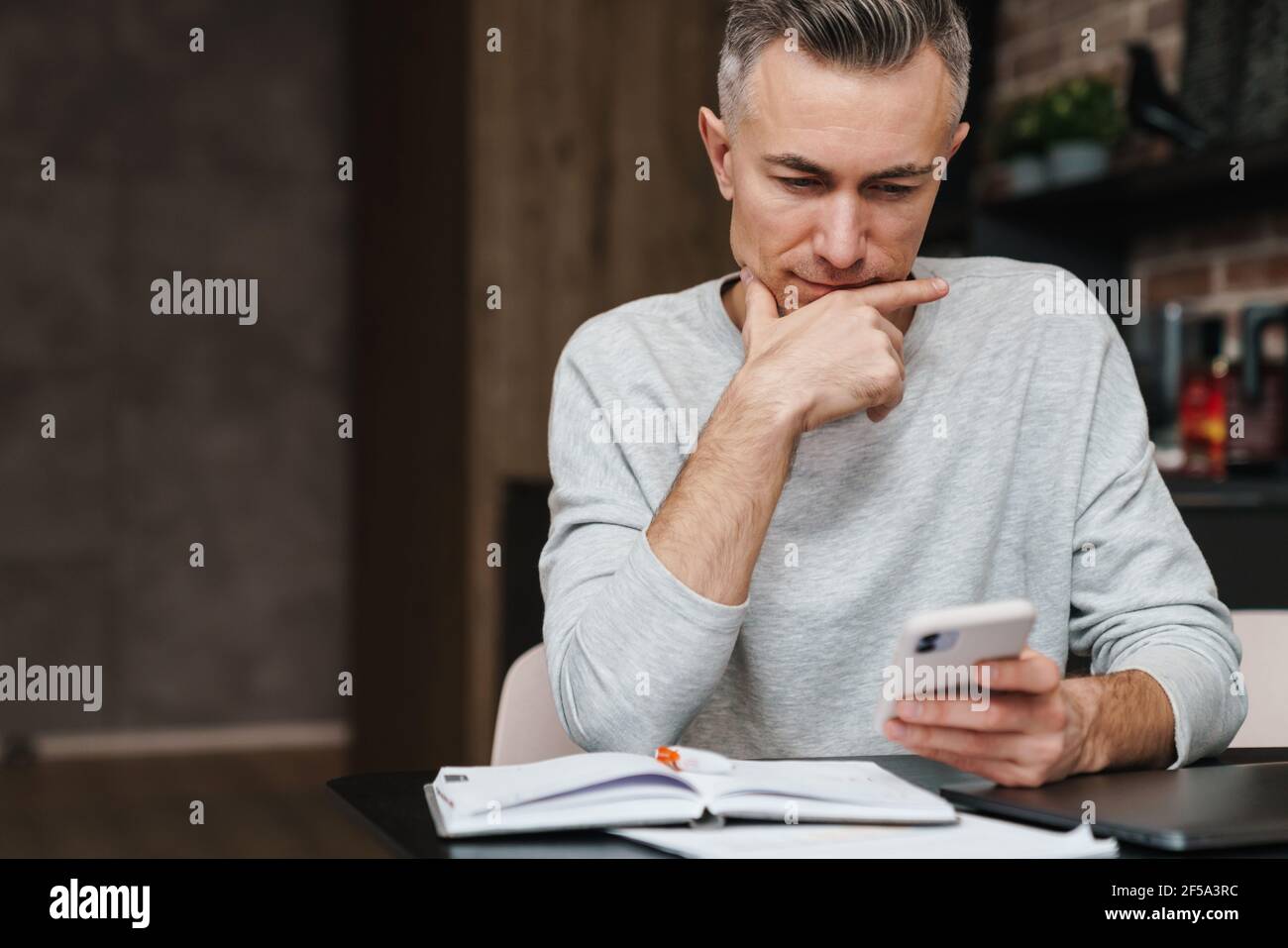 Focused handsome man using mobile phone while working at home Stock Photo