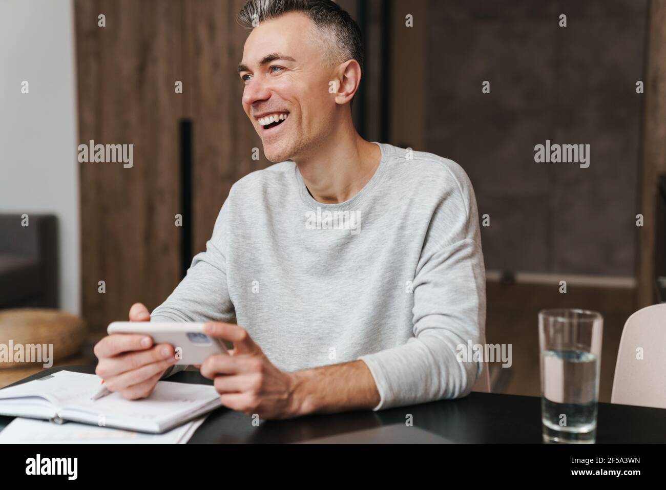 Handsome happy middle aged man using smartphone at home Stock Photo