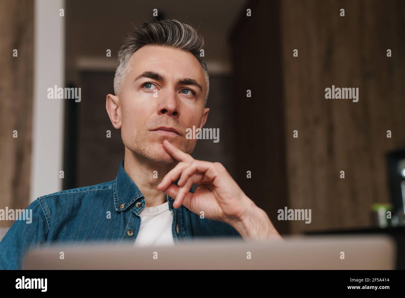 Focused handsome man using laptop while sitting on couch at home Stock Photo