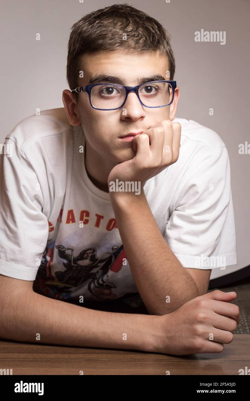 Young boy holding hand under head, looking upset Stock Photo Alamy