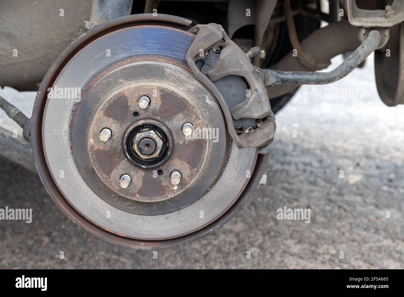 Rusty back car wheel hub with brake disc at tire shop. Car without a wheel while replacing on the tire service center. Closeup view Stock Photo