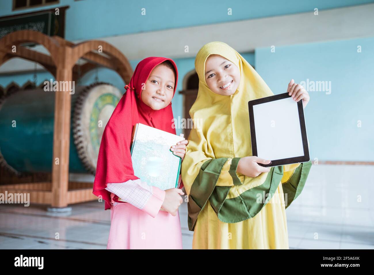 two kid girl Muslim smiling holding blank tablet and al quran book ...