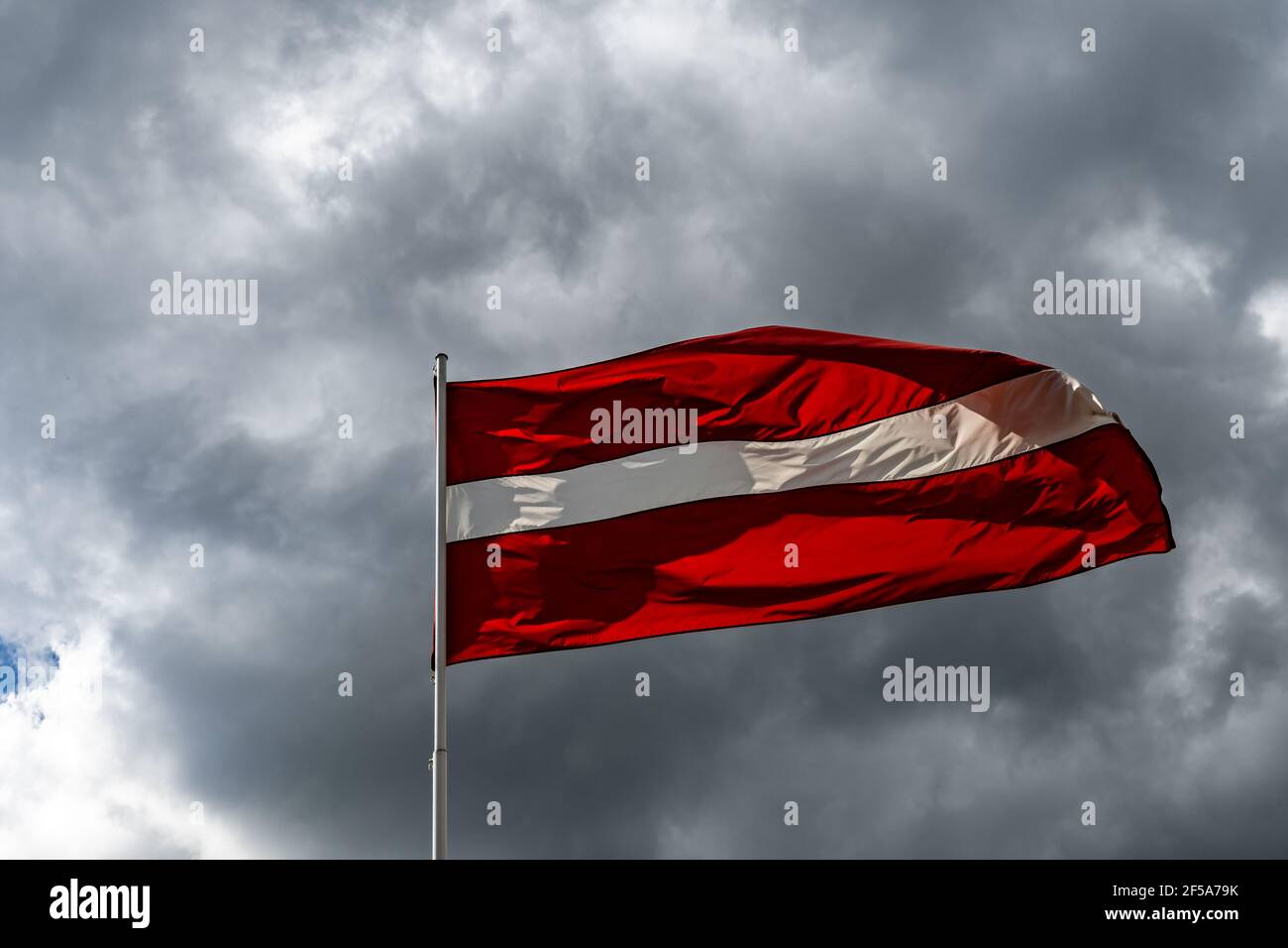 Flag of the Republic of Latvia. Flag of Latvia against the blue sky. Copy space. Stock Photo
