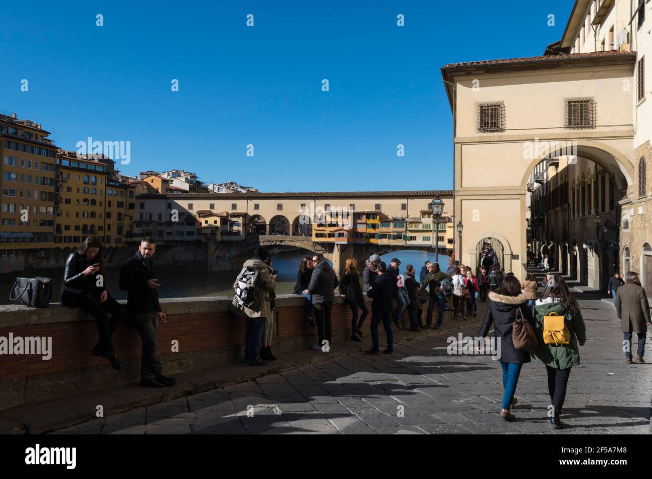 Tourist walking along Lungarno degli Archibusieri street with the Ponte Vecchio in the background, Florence, Tuscany, Italy. Stock Photo