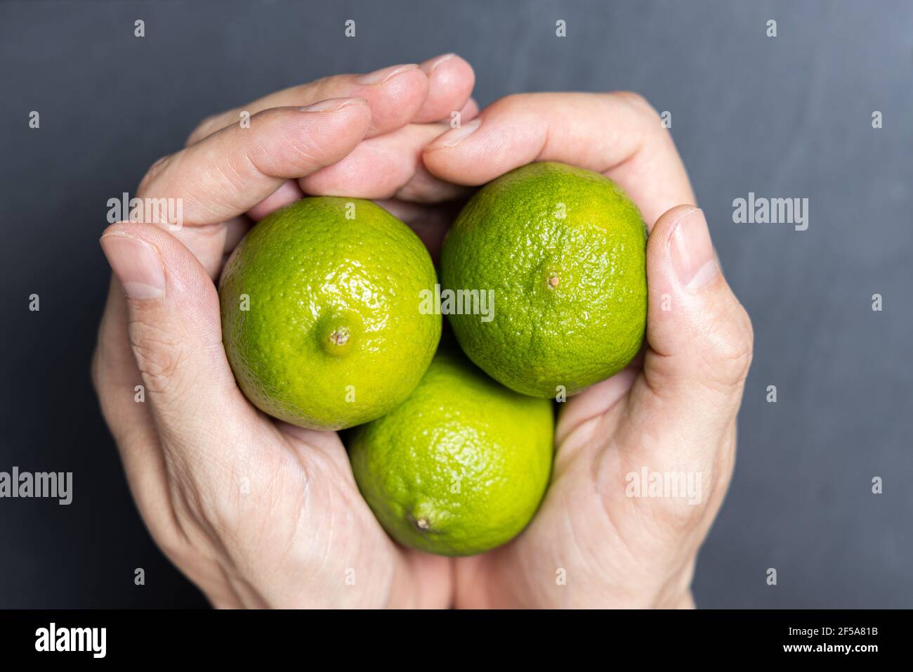 Man's hands holding three fresh limes Stock Photo Alamy