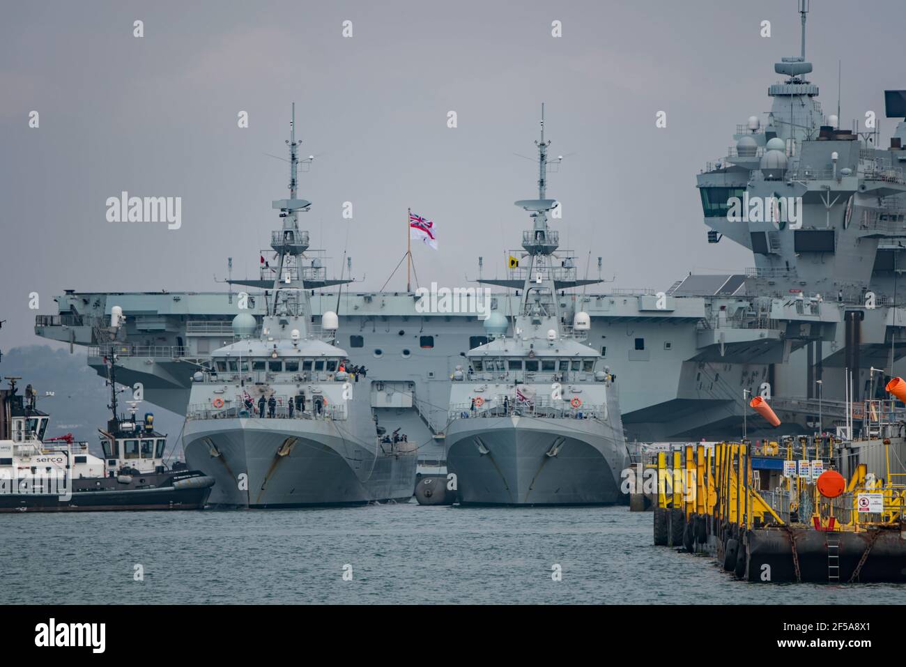 The Royal Navy offshore patrol vessel HMS Trent (P224) being manoeuvred alongside her sister ship HMS Spey. In the background is HMS Queen Elizabeth. Stock Photo