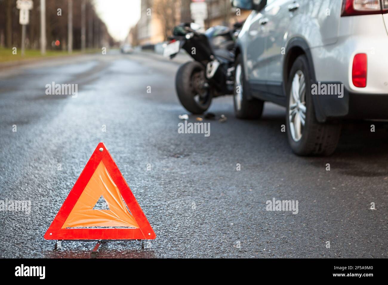 Warning triangle sign standing on a distance from road collision with a motorbike and car Stock Photo