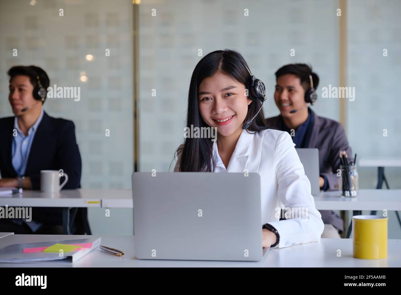 Female operator with her team before communicates with the client. Stock Photo