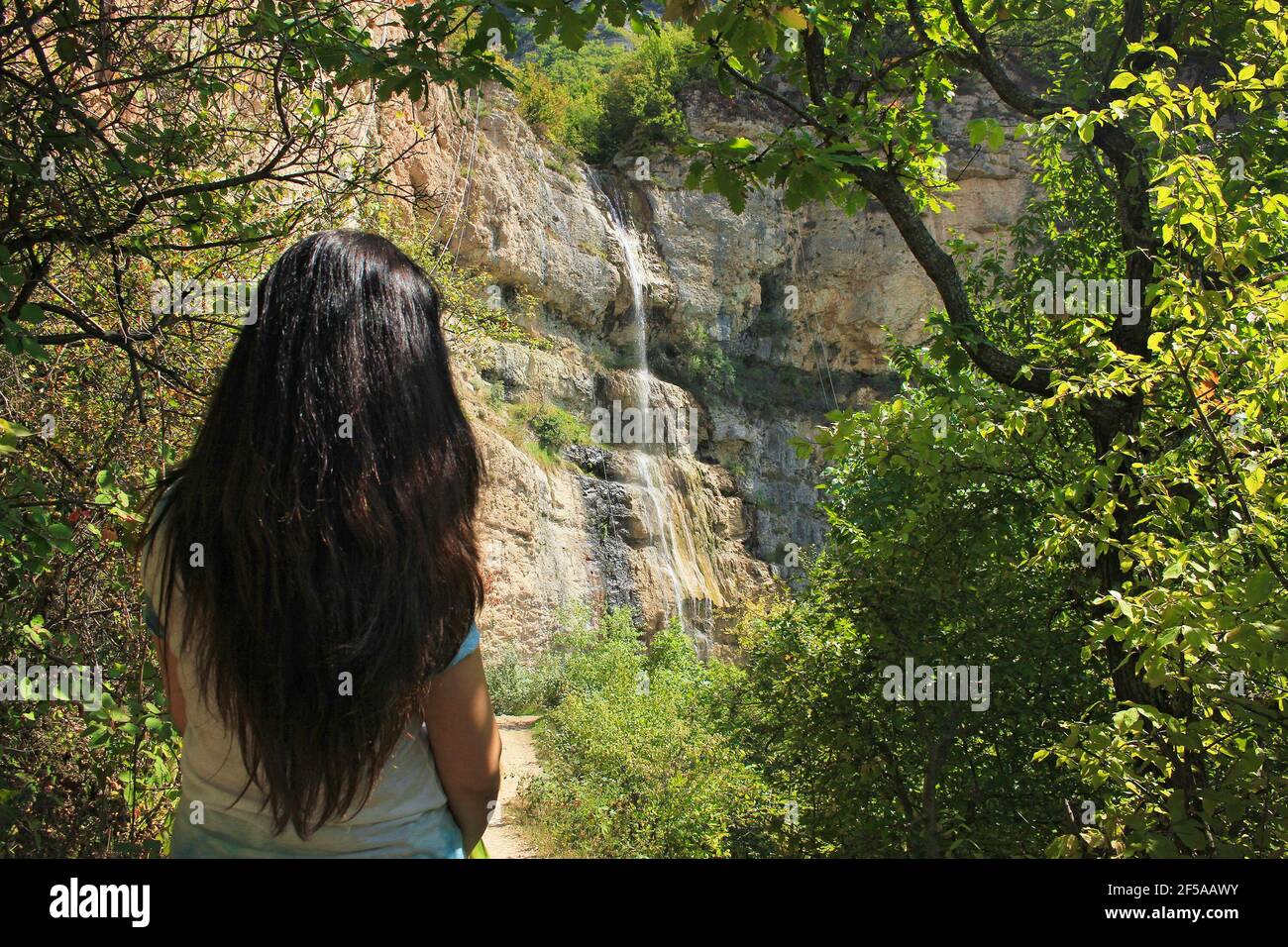 The girl looks at a beautiful waterfall. Azerbaijan. Afurja village. Stock Photo