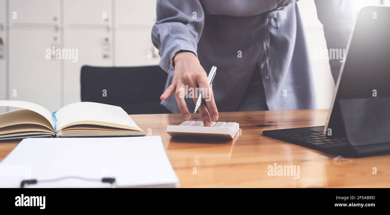 Accountant hand holding pen and using calculator to analyze sales ...