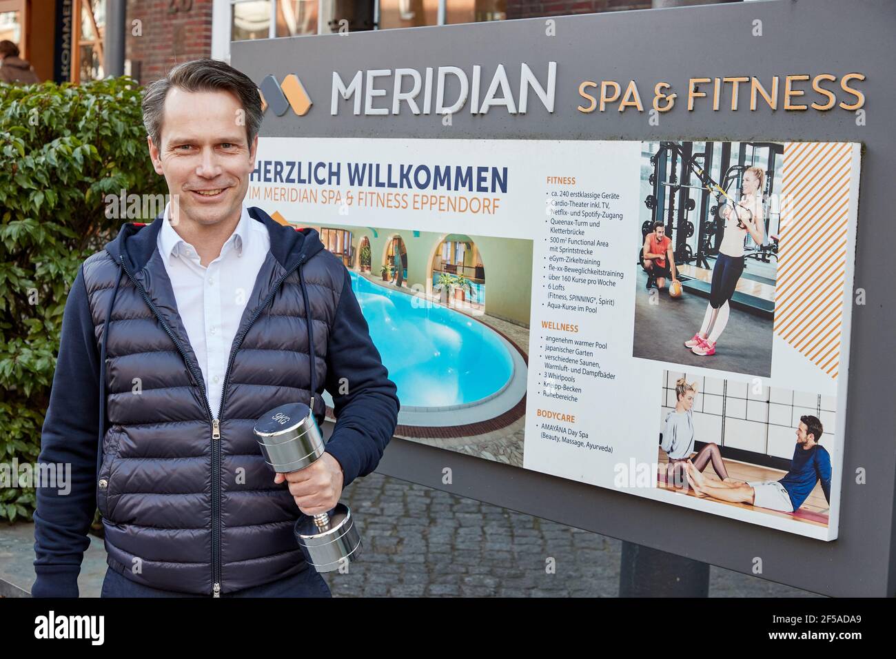 Hamburg, Germany. 25th Mar, 2021. Andre Nagel, managing director of  Meridian Spa & Fitness, stands with a dumbbell next to the entrance of  Meridian Spa & Fitness on Quickbornstraße. Credit: Georg Wendt/dpa/Alamy