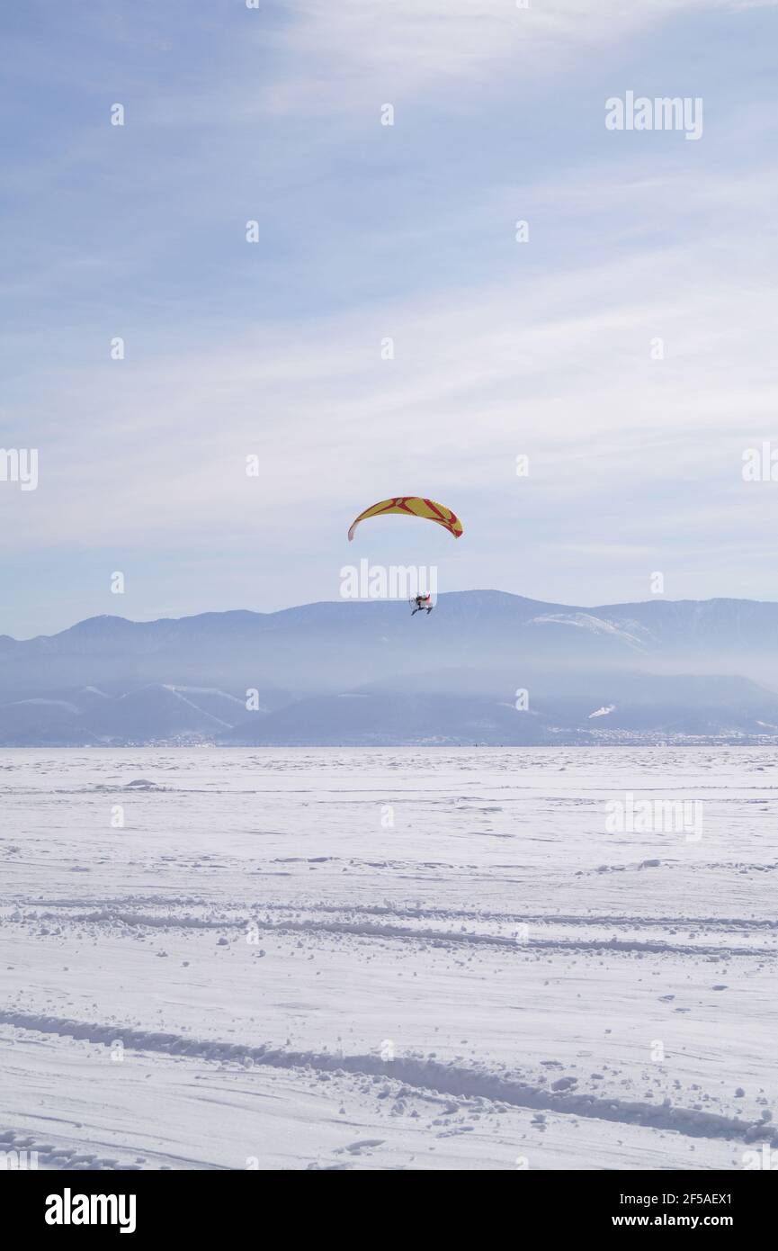 A man of 40-45 years old flies on a paraglider over the ice of L Stock Photo