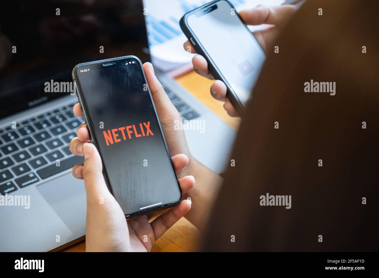 CHIANG MAI, THAILAND - FEB 11, 2021 : Woman and friend holding Phone with Netflix logotype on a screen and sharing her movie list. Stock Photo