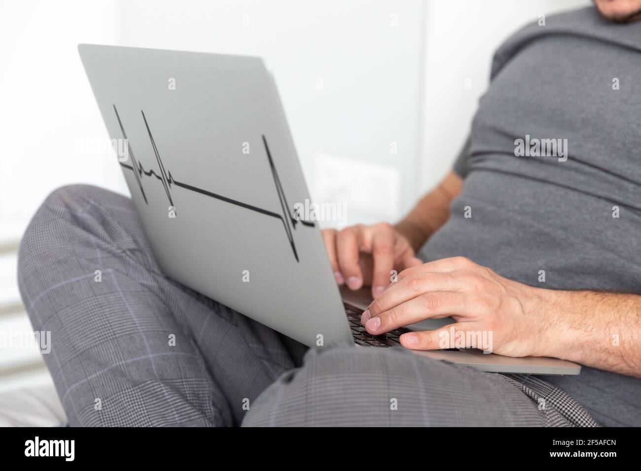 A man works on a computer in bed close up hands Stock Photo