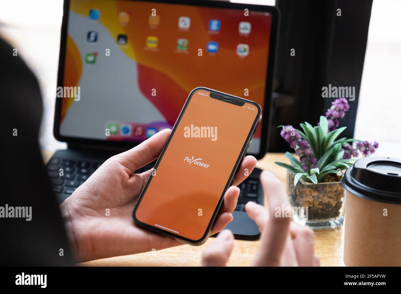 CHIANG MAI, THAILAND - Mar 08, 2021 Woman using Payoneer on iPhone with tablet on background. Payoneer is a worldwide online payment system Stock Photo