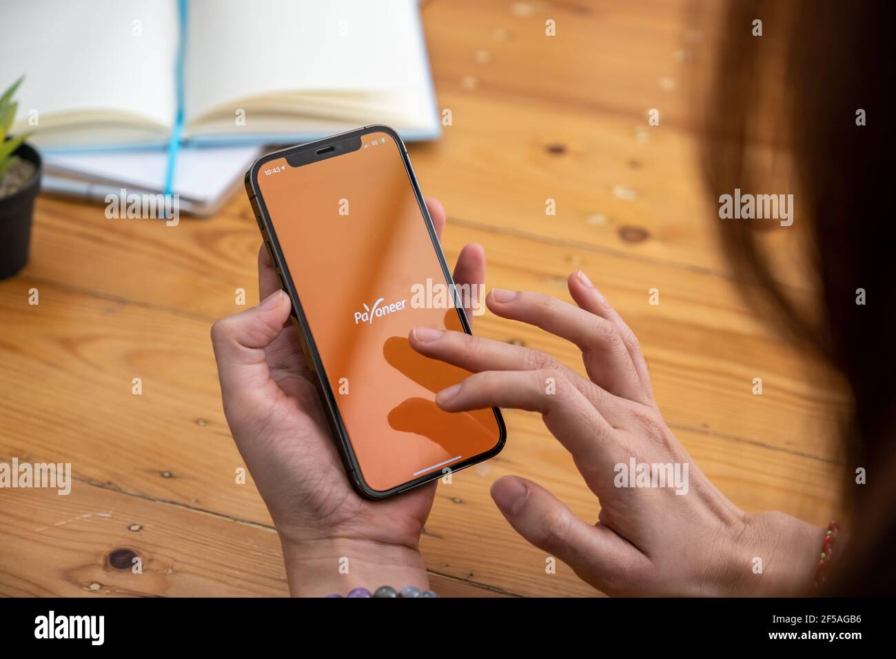 CHIANG MAI, THAILAND - Mar 08, 2021 Woman using Payoneer on iPhone with tablet on background. Payoneer is a worldwide online payment system Stock Photo