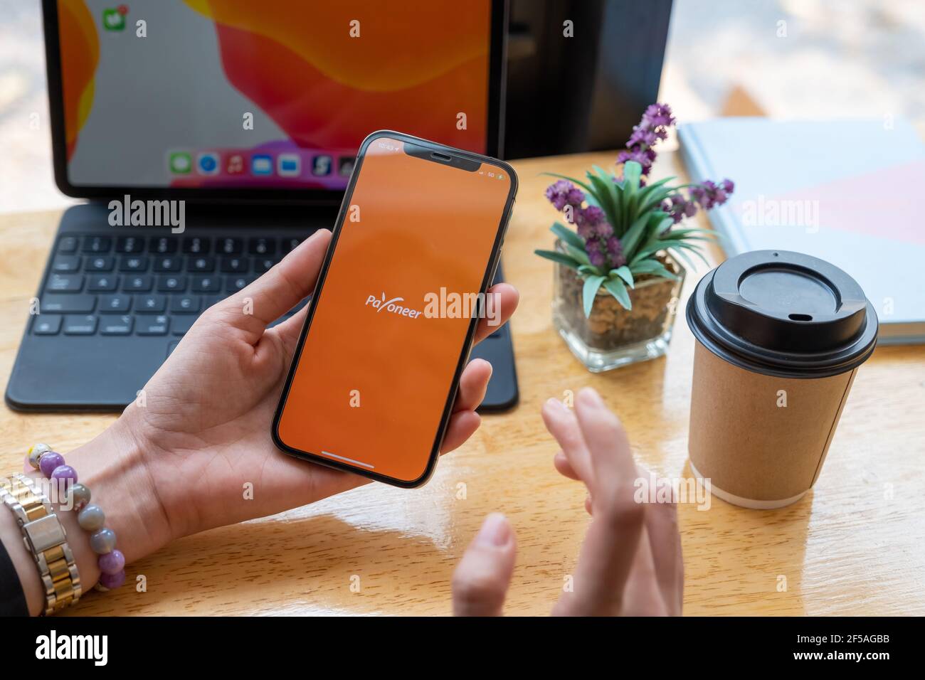 CHIANG MAI, THAILAND - Mar 08, 2021 Woman using Payoneer on iPhone with tablet on background. Payoneer is a worldwide online payment system Stock Photo