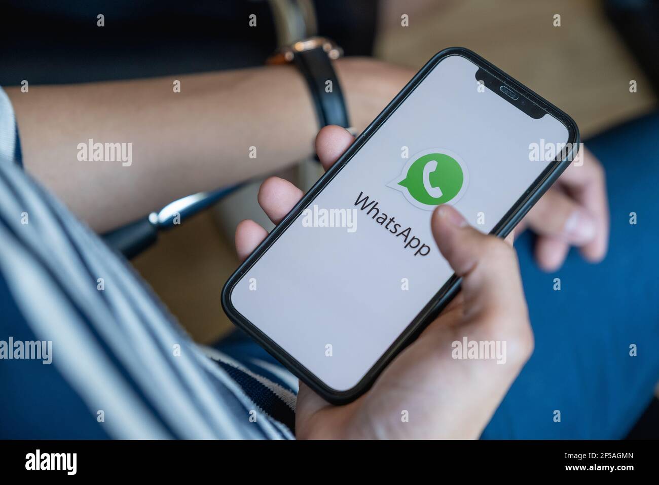 CHIANG MAI, THAILAND - FEB 1, 2032 : Man holding iPhone with Whatsapp logo on Cellphone Screen. Stock Photo