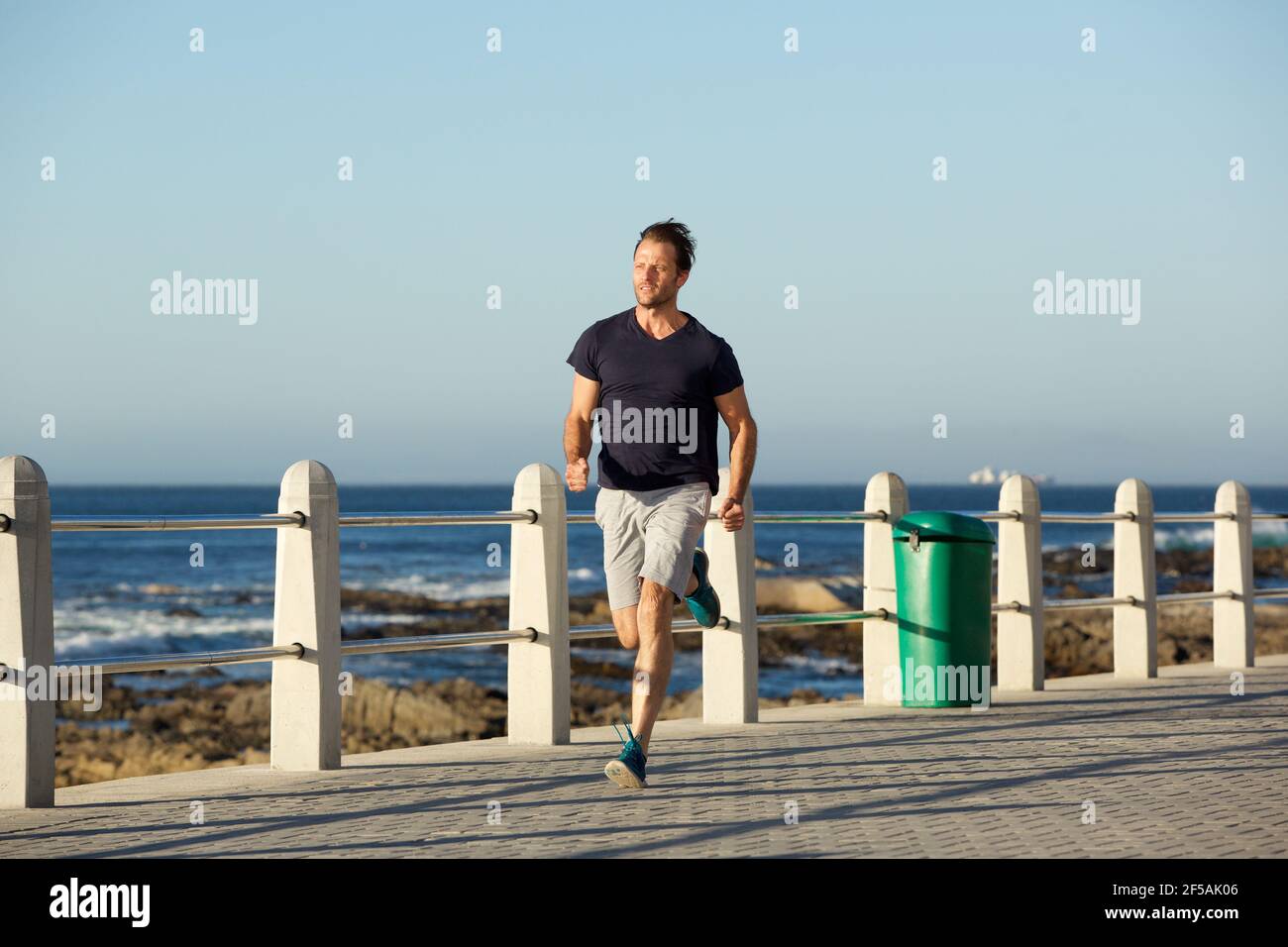 Full body portrait of middle age sports man running outside Stock Photo