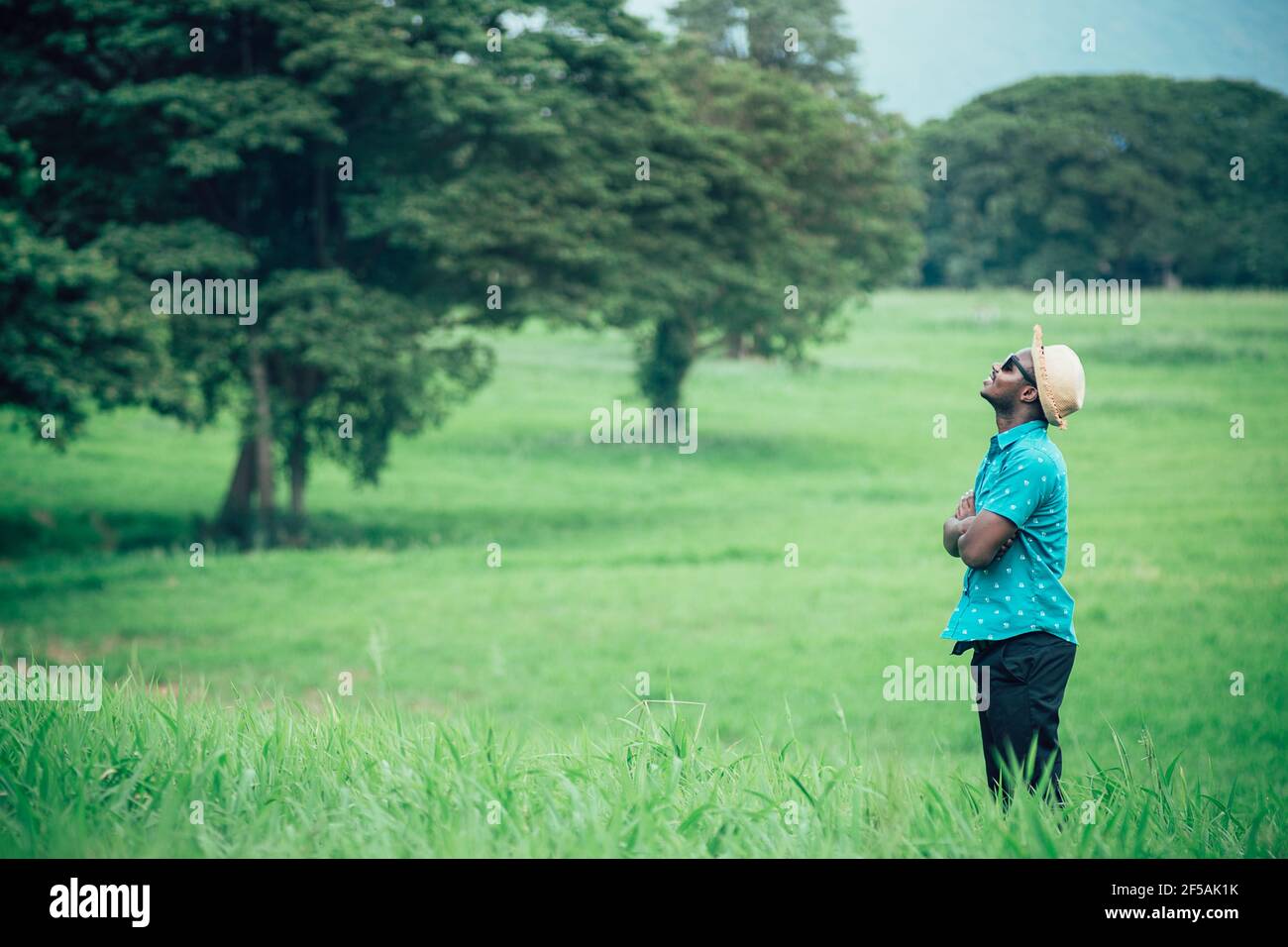 African traveler man stand with smile happily among green meadows Stock Photo