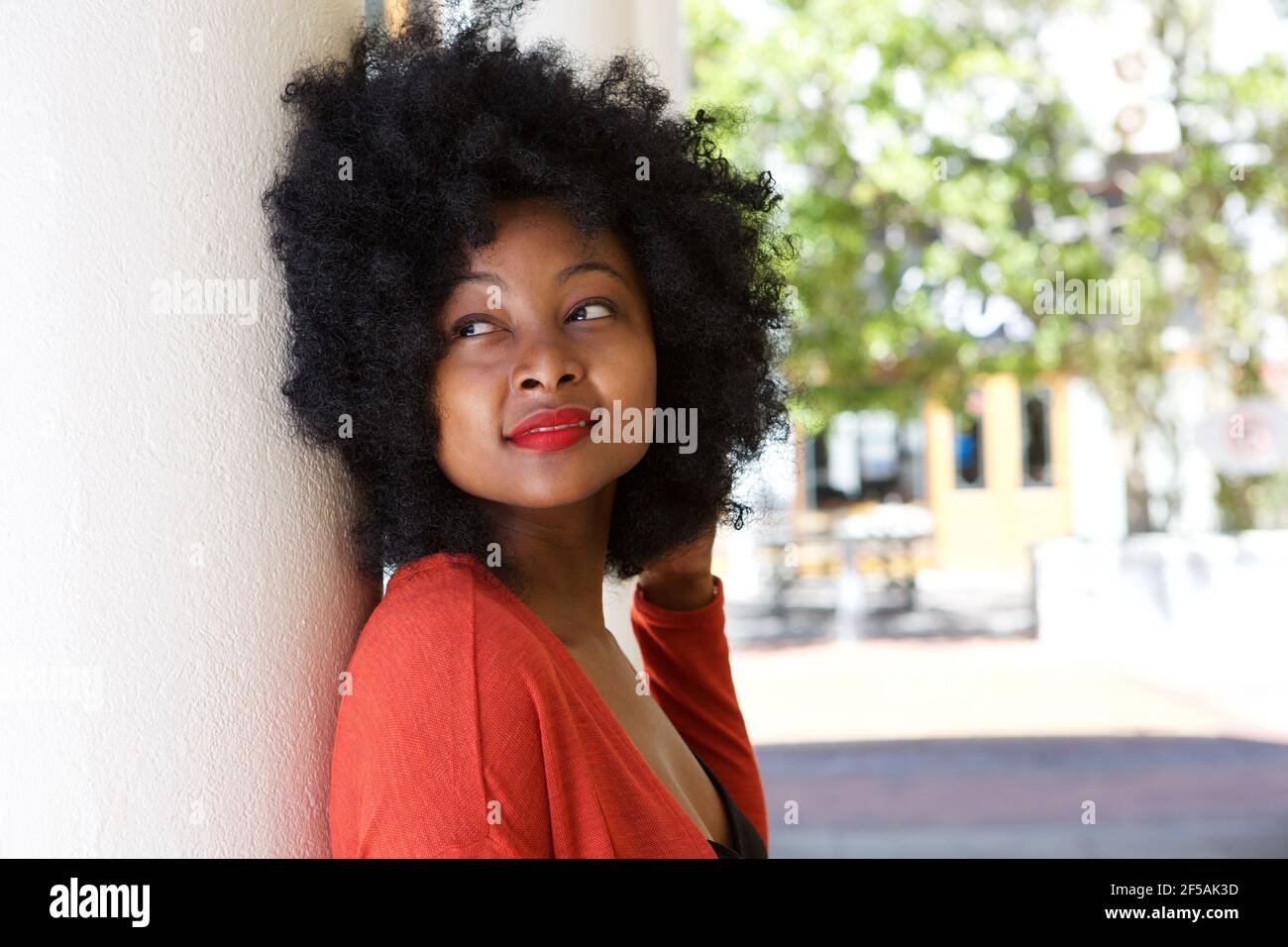 Close up portrait of young woman outside leaning against wall daydreaming Stock Photo